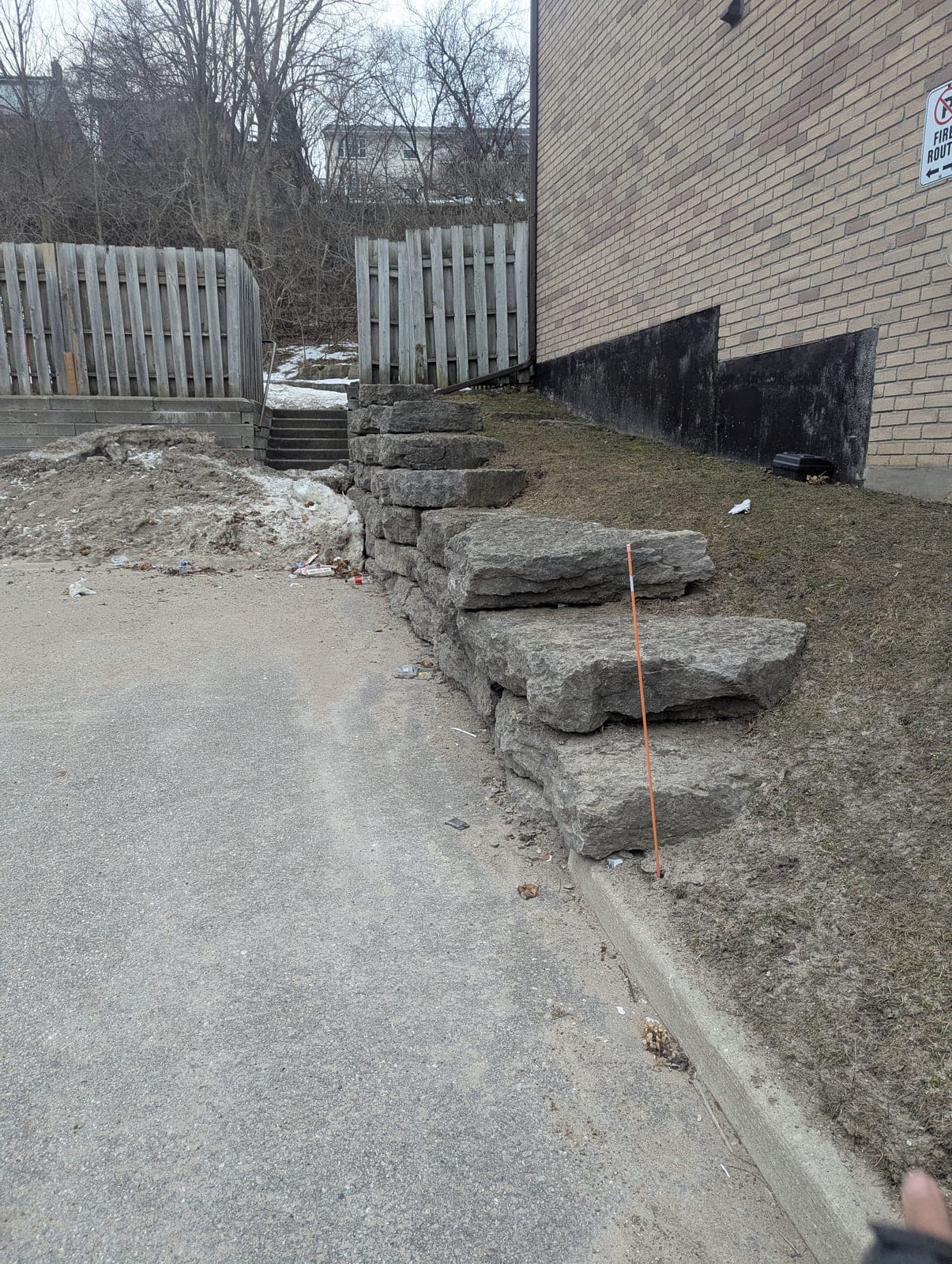 Stacked armour stone retaining wall and steps running along a paved laneway