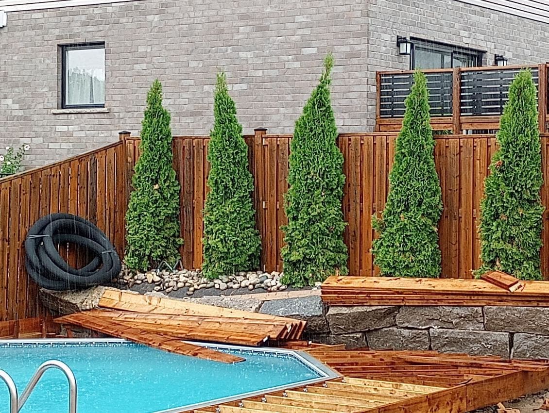 Natural boulder retaining wall edging a cedar garden bed beside a backyard pool deck