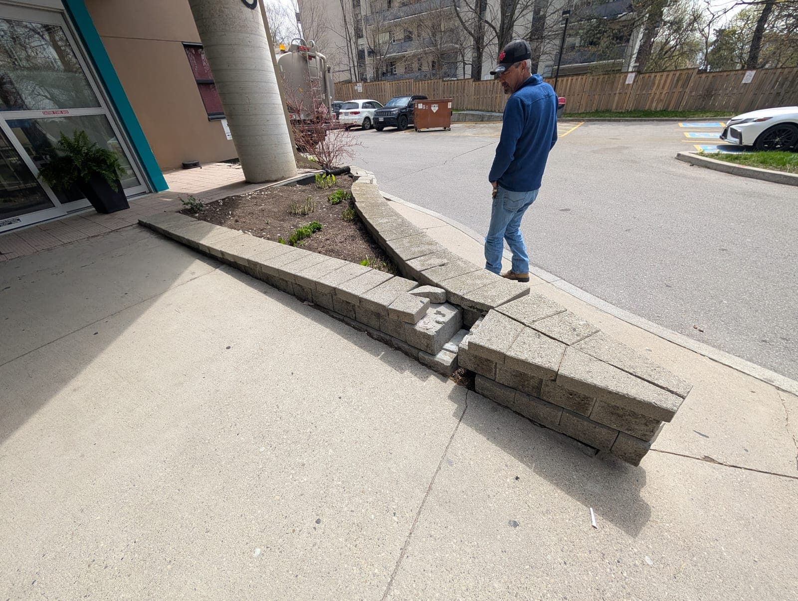 Collapsing segmental block retaining wall being assessed for repair at a commercial building