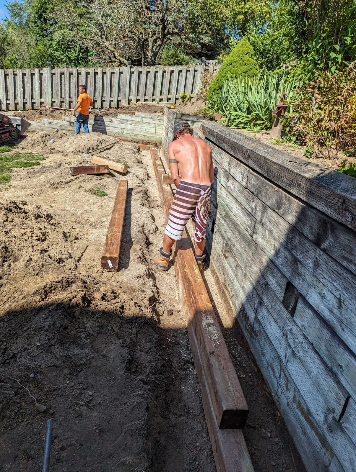 Large timber tie retaining wall holding back a raised garden bed in a residential backyard