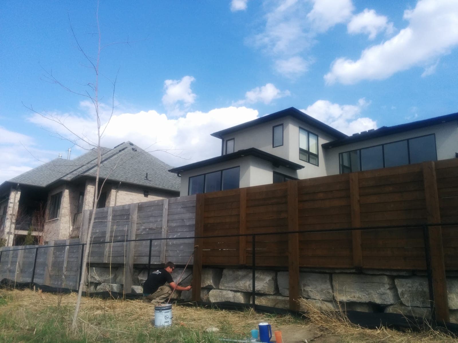 Stacked natural stone retaining wall topped with a horizontal wood privacy fence along a backyard grade change
