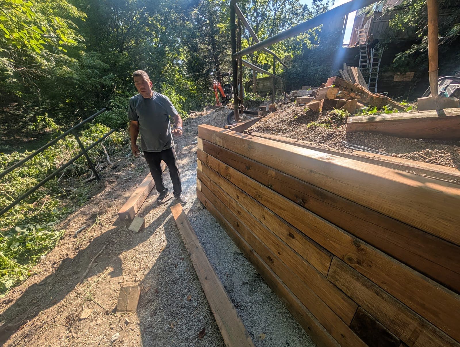 Newly constructed timber retaining wall holding back a wooded hillside during installation