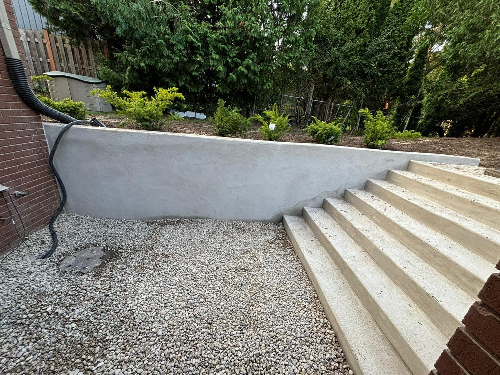 Smooth parged poured concrete retaining wall with steps in a landscaped London, Ontario backyard