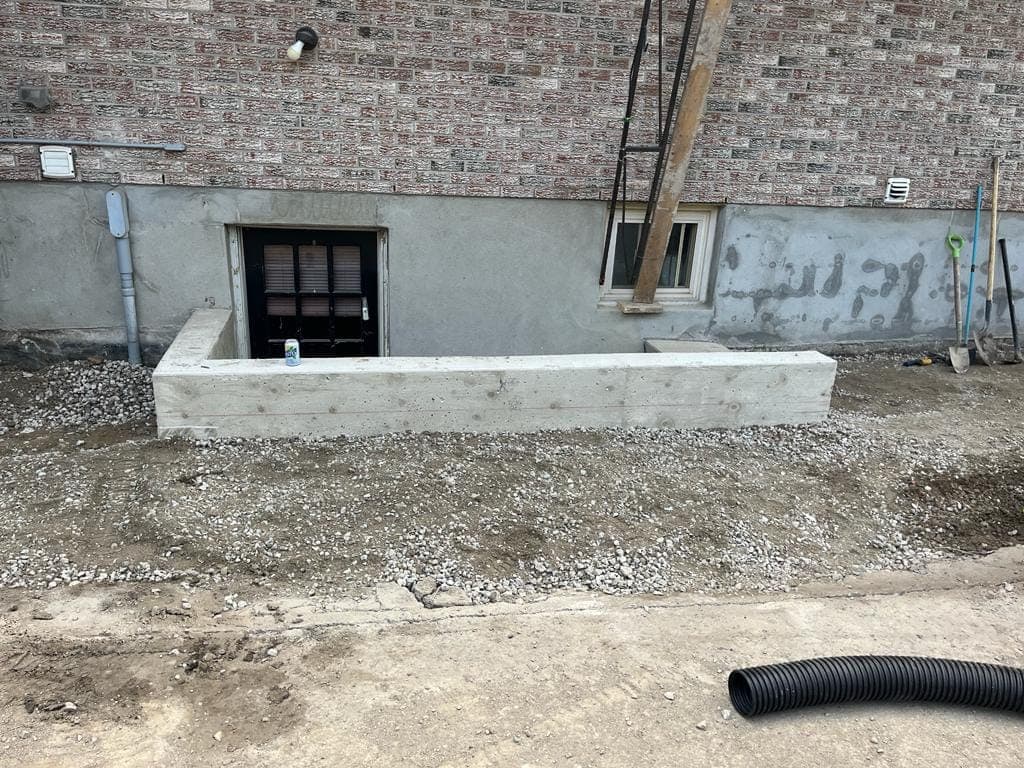 Poured concrete retaining wall enclosing a basement walkout entrance