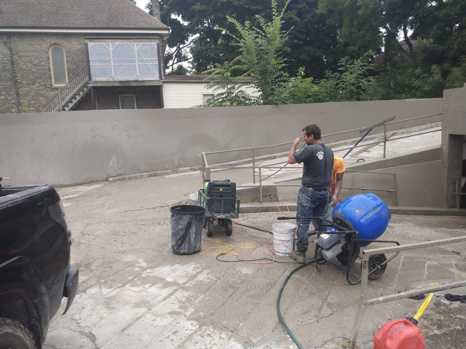 Smooth poured concrete retaining wall lining a below-grade access ramp beside a building