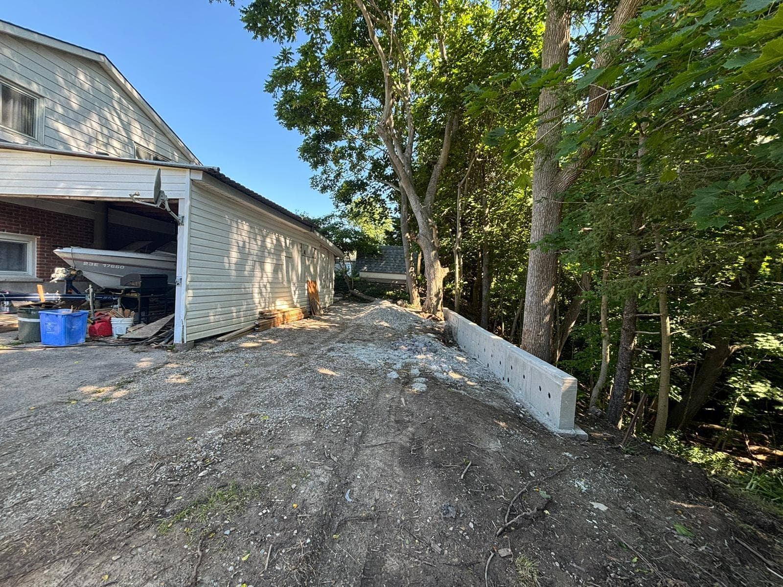 Repaired poured concrete retaining wall with weep-hole drainage stabilizing a slope beside a London, Ontario driveway