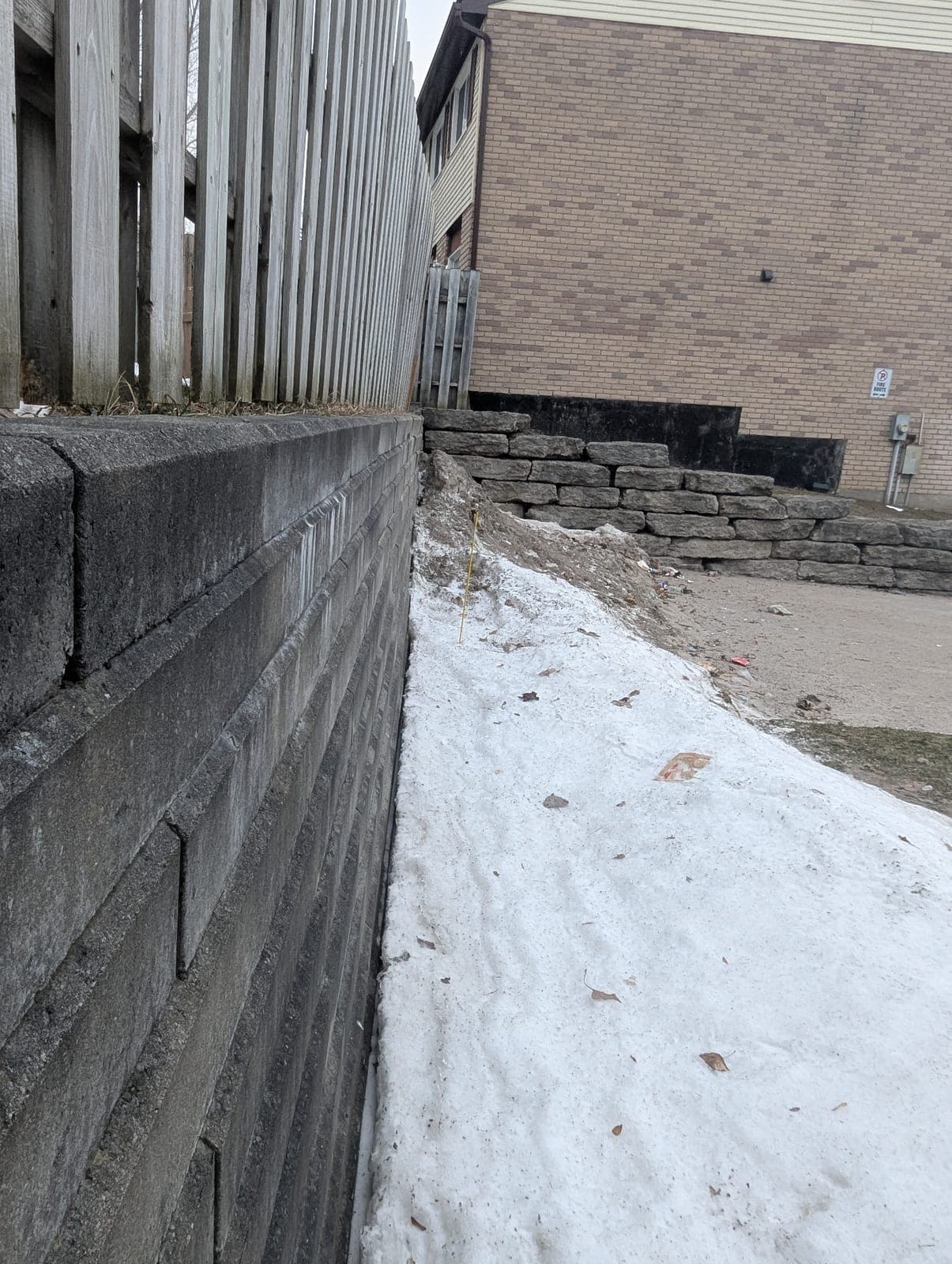 Segmental block retaining wall with a terraced natural stone wall in the background