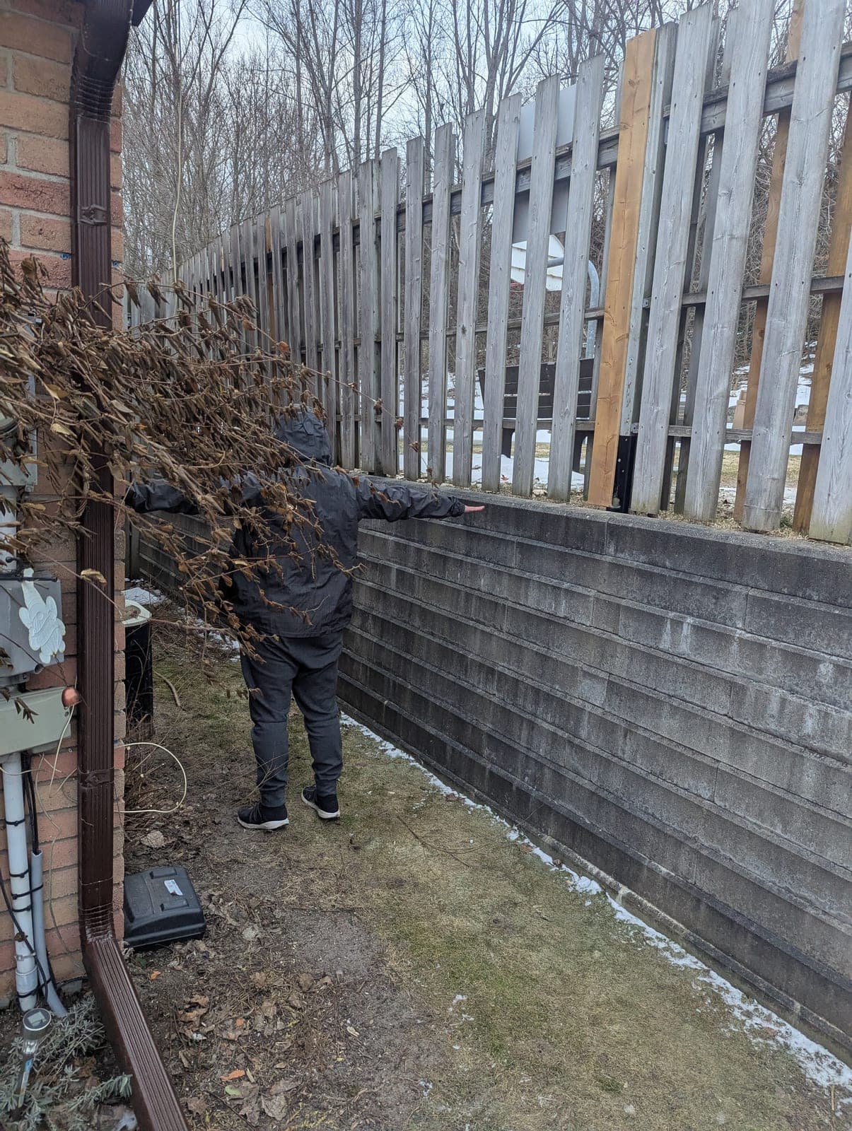 Segmental concrete block retaining wall running along a wood fence line