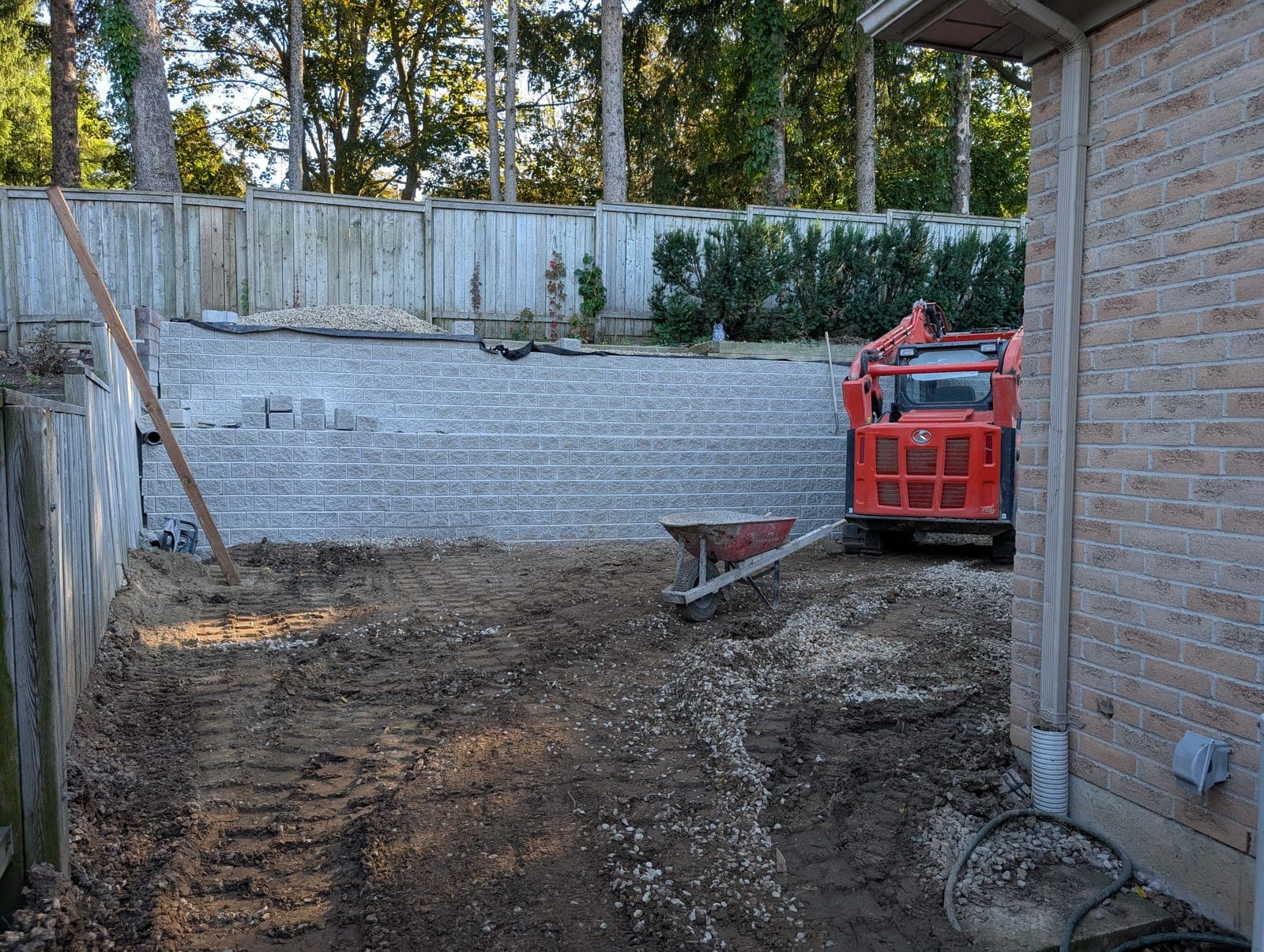 Curved segmental concrete block retaining wall built along a backyard fence line