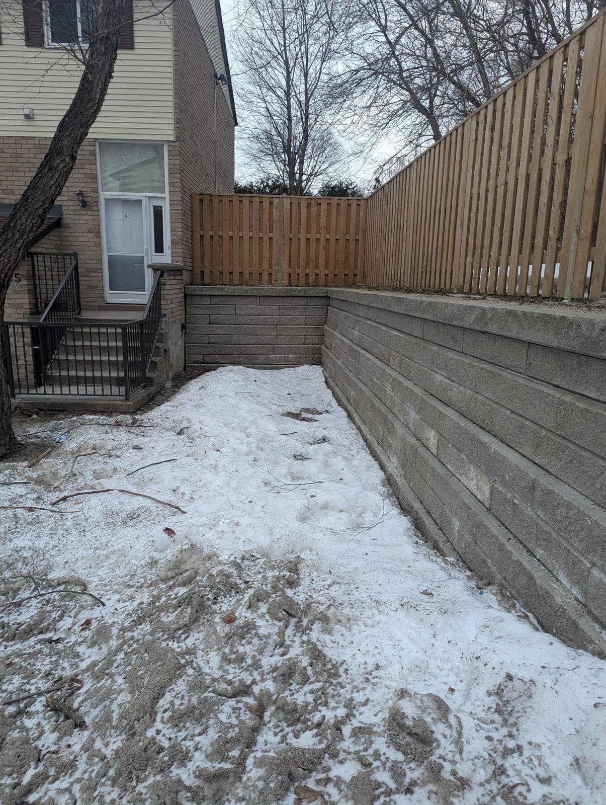 Finished segmental concrete block retaining wall topped with a wood privacy fence