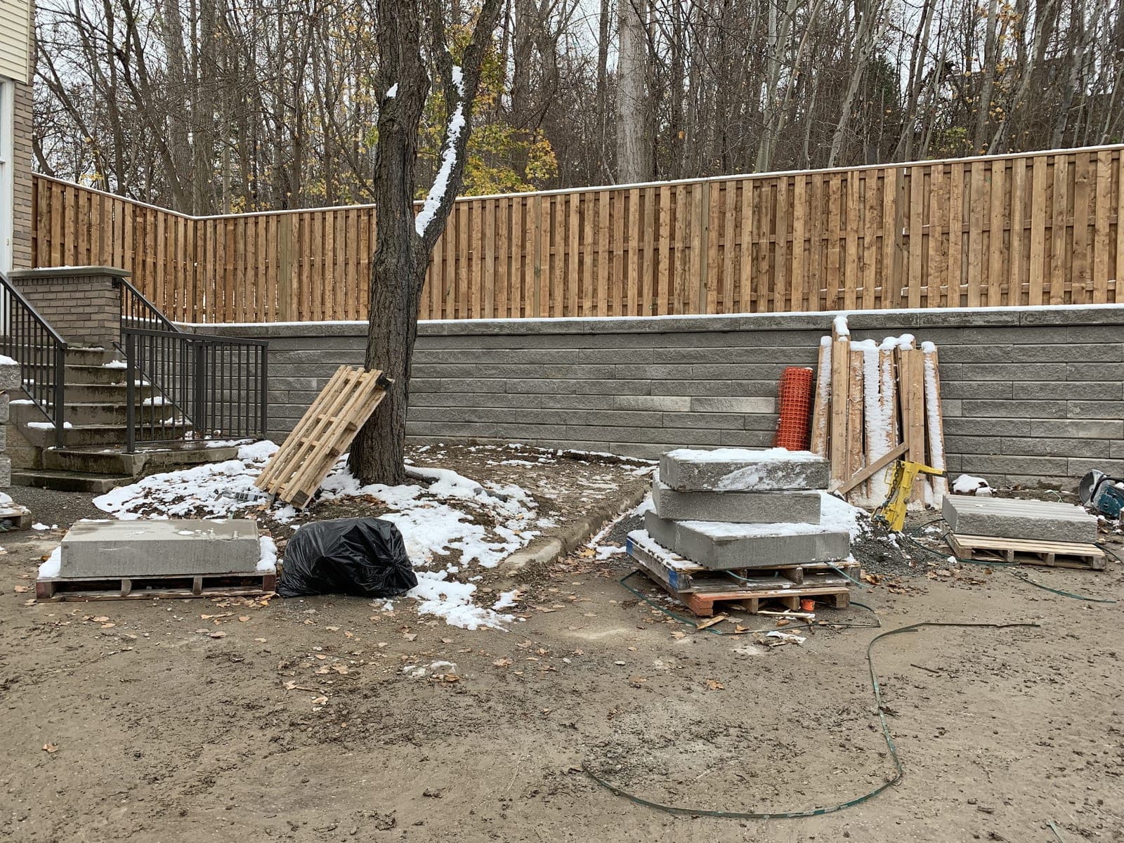Grey segmental block retaining wall with integrated steps and railing in a landscaped backyard
