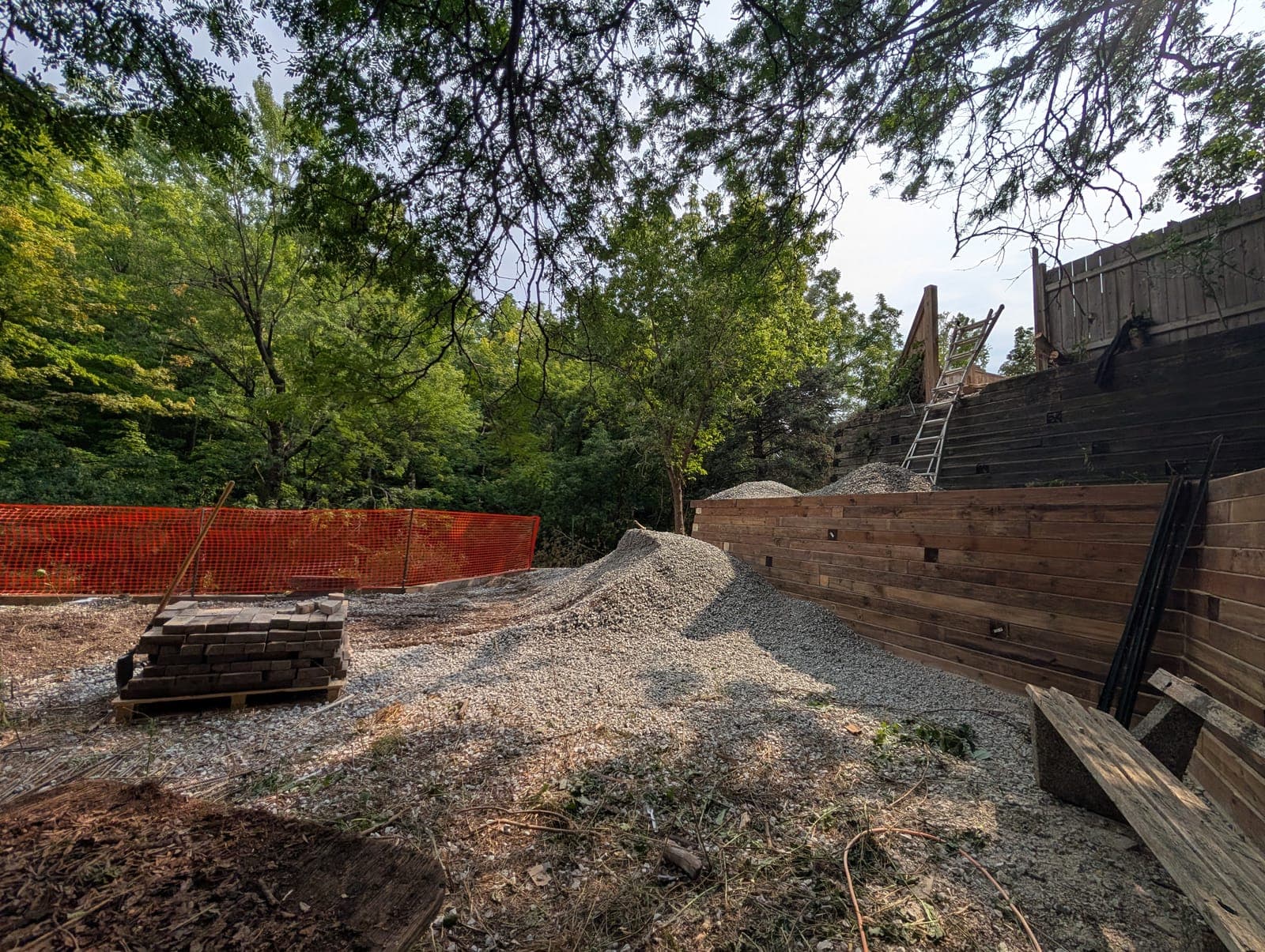 Tall tiered timber retaining wall alongside a gravel work area in a backyard