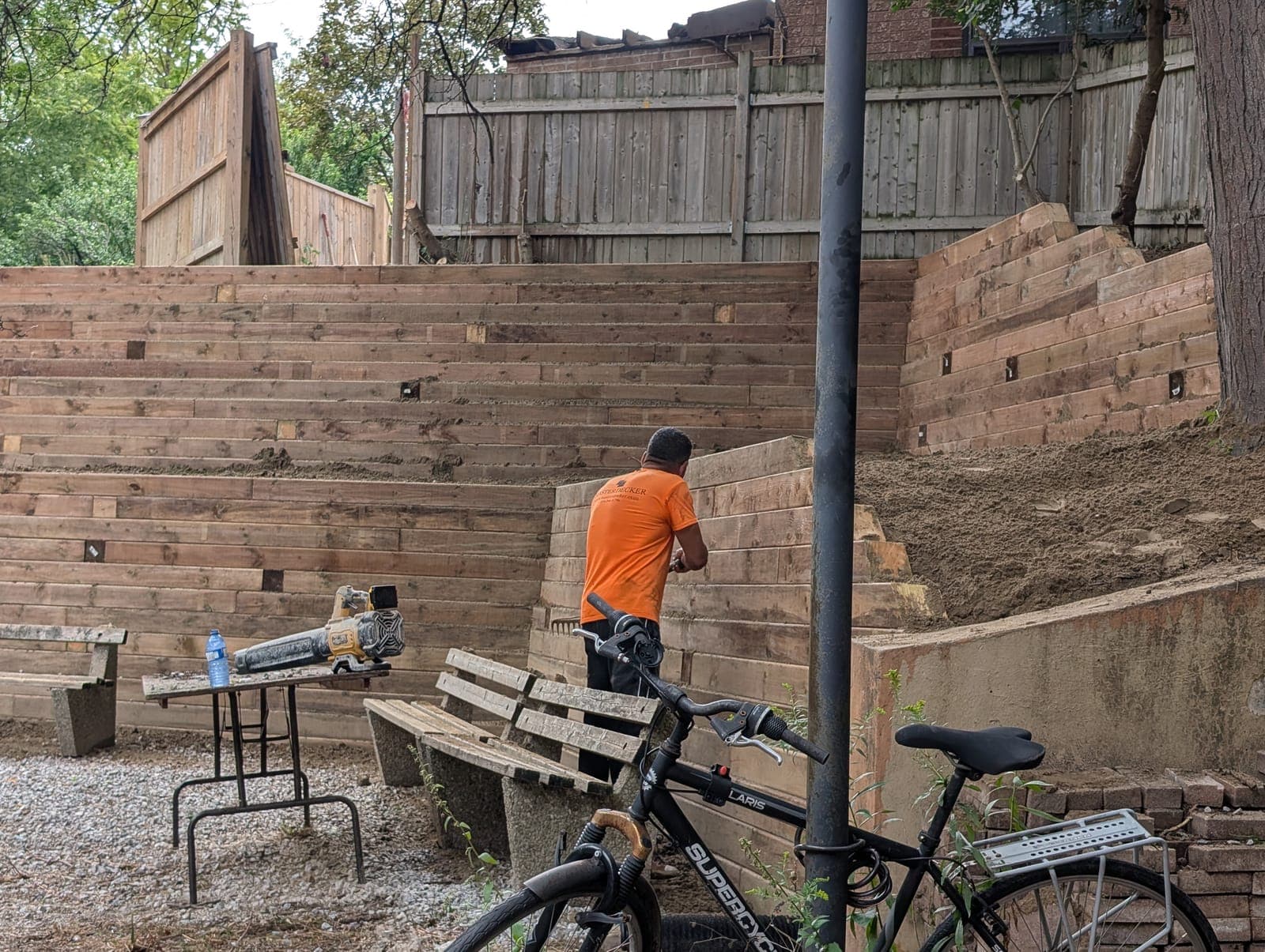 Amphitheater-style terraced timber retaining walls curving around a gravel backyard seating area