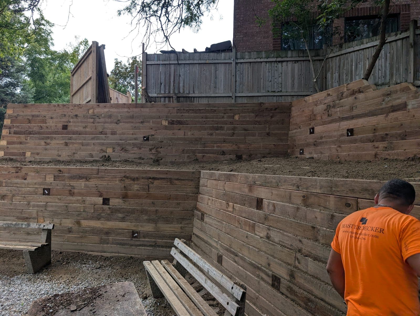 Multi-tiered timber retaining wall creating terraced grades in a landscaped backyard