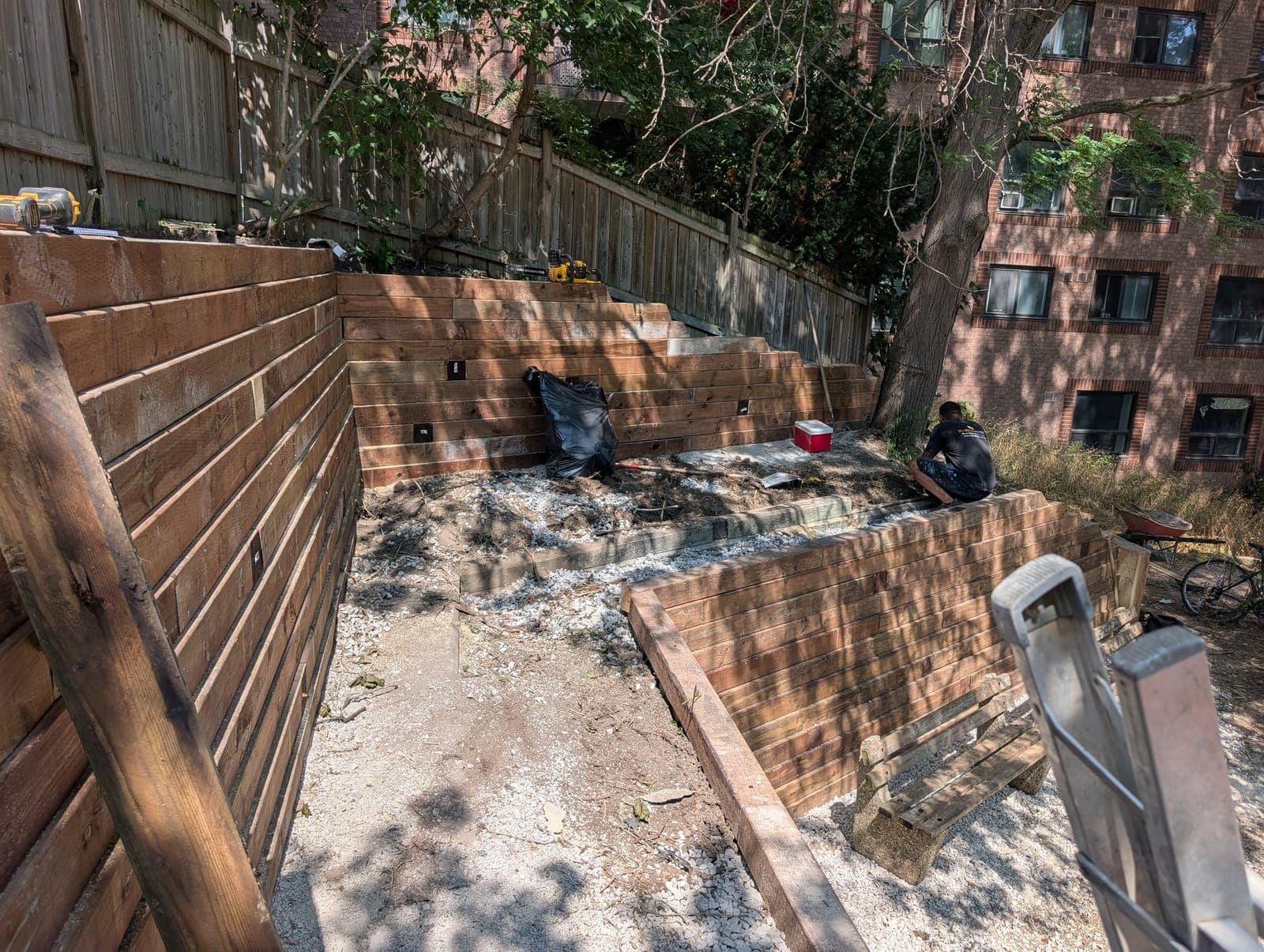 Terraced timber retaining walls forming a backyard enclosure under construction in an urban setting