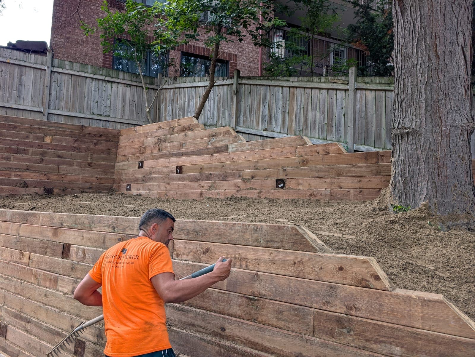 Terraced timber retaining wall rising up a fenced backyard slope with integrated step lighting