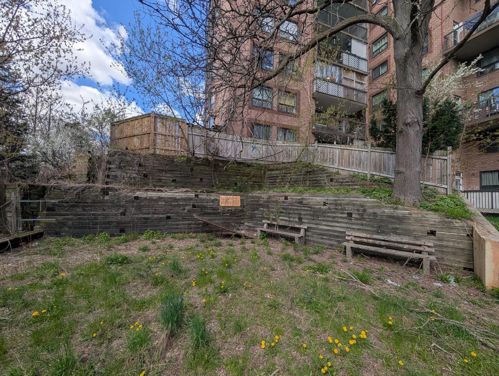 Large terraced timber retaining wall forming stepped tiers behind an apartment building