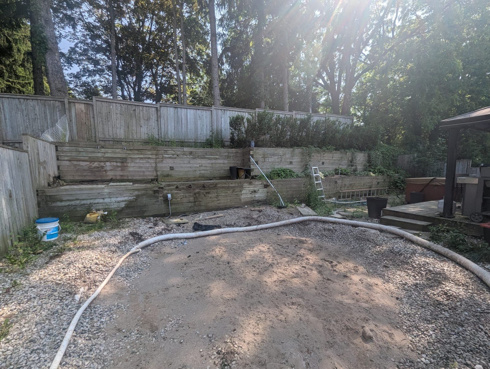 Two-tier terraced timber retaining wall creating layered garden beds along a backyard property line