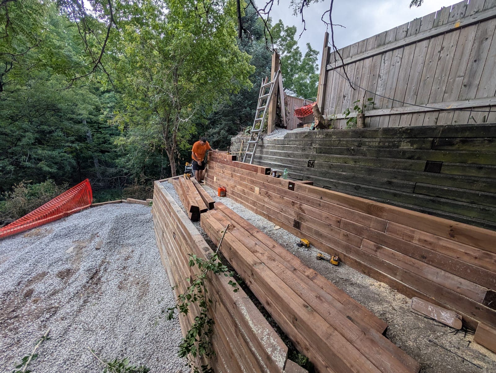 Terraced timber retaining wall stepping down a wooded backyard slope