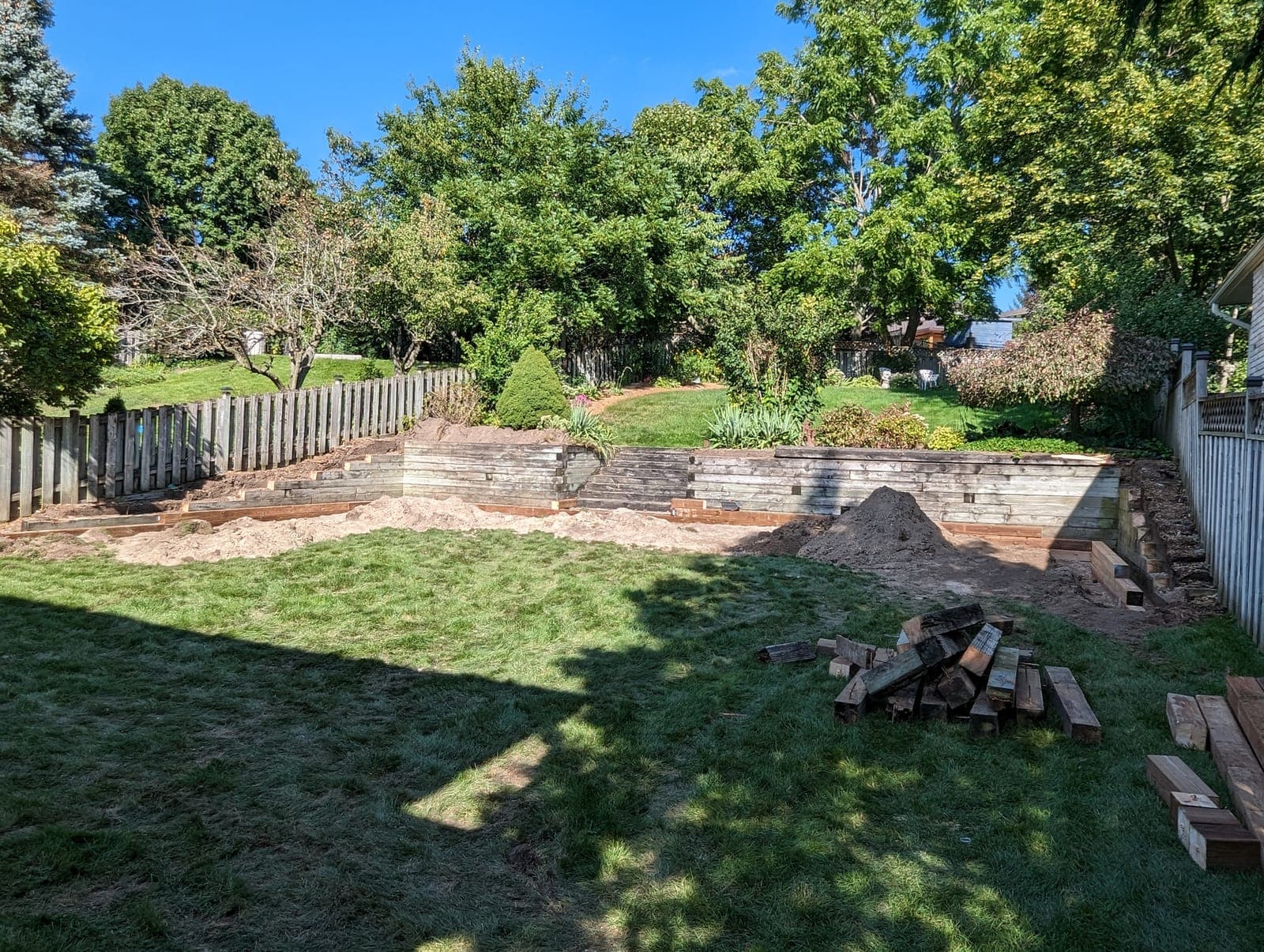 Tiered timber retaining wall with layered garden beds along a backyard slope