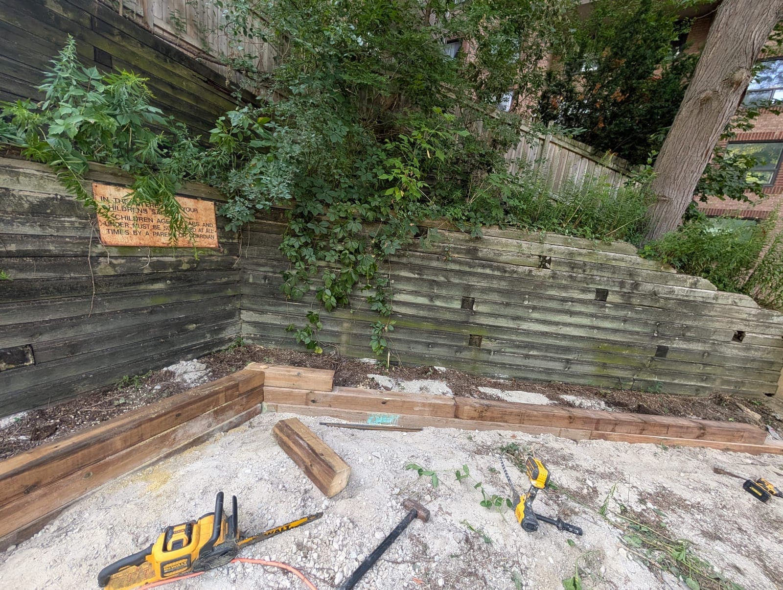 Tiered timber retaining wall forming stepped garden terraces against a backyard slope