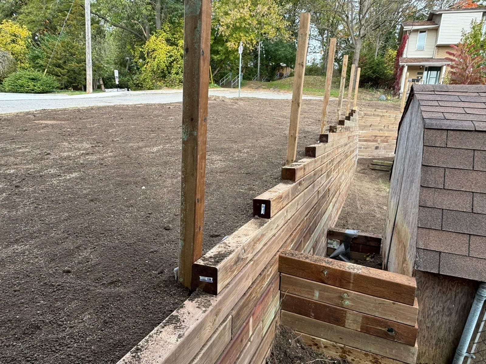 Tiered timber retaining wall stabilizing a graded residential lot with support posts