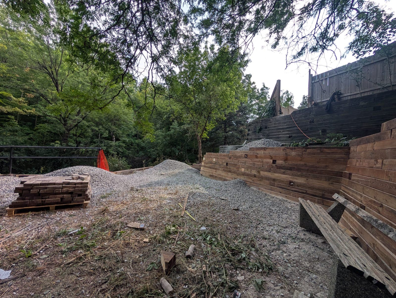 Tiered timber retaining wall with a compacted gravel base in a wooded backyard
