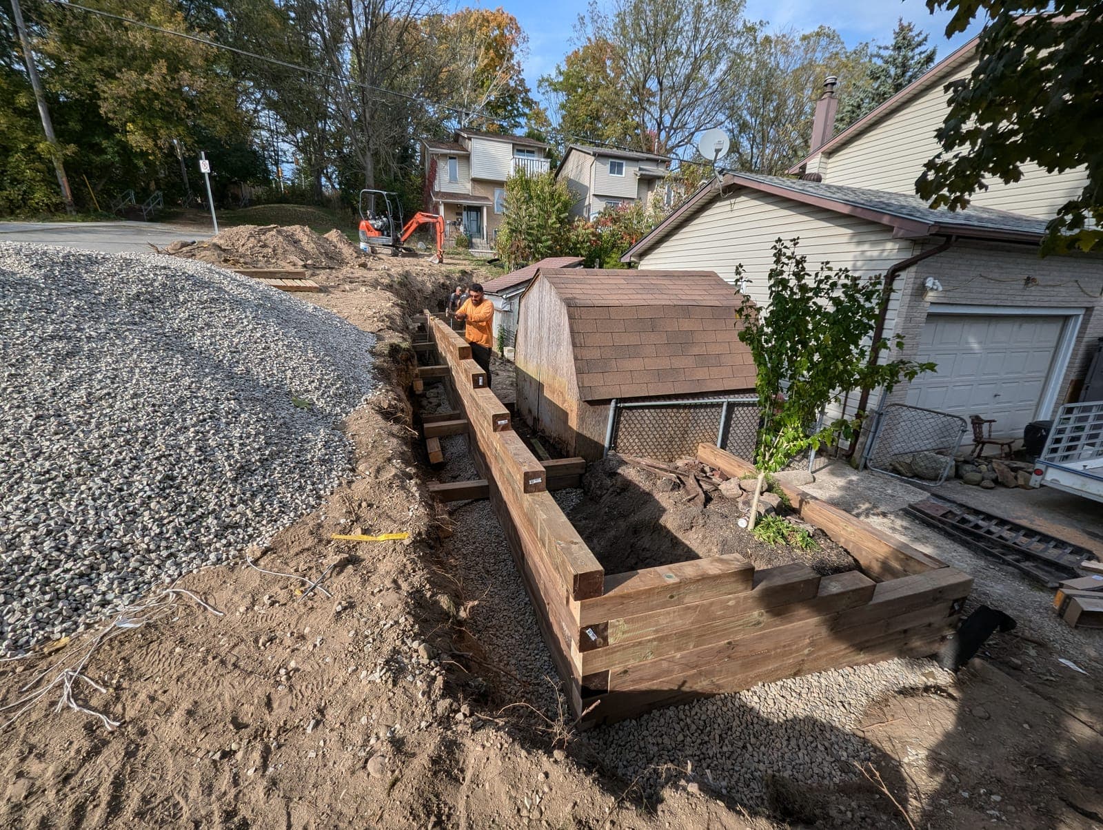 Timber beam retaining wall with corner returns holding back a graded driveway
