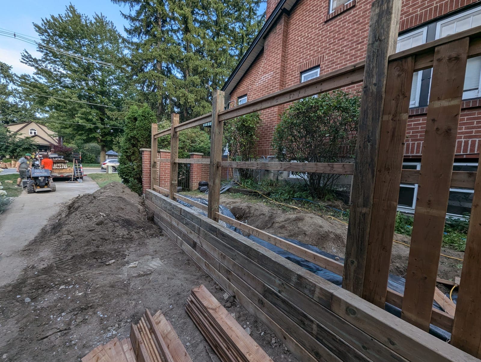 Timber retaining wall under construction alongside a residential driveway grade change