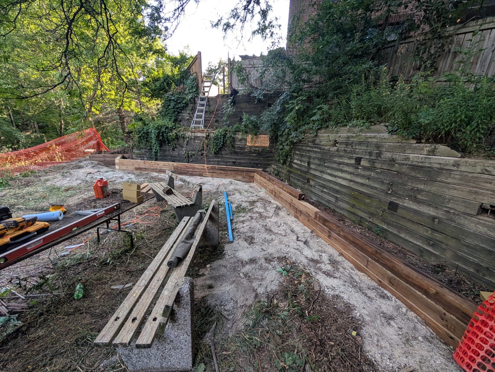 Timber retaining wall holding back soil to create a level backyard behind a residential building