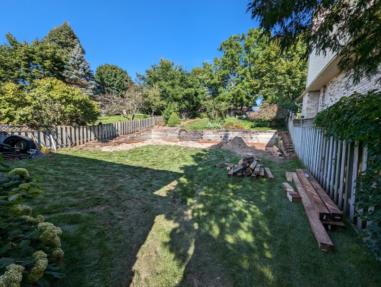 Timber retaining wall creating a tiered grade change across a landscaped backyard