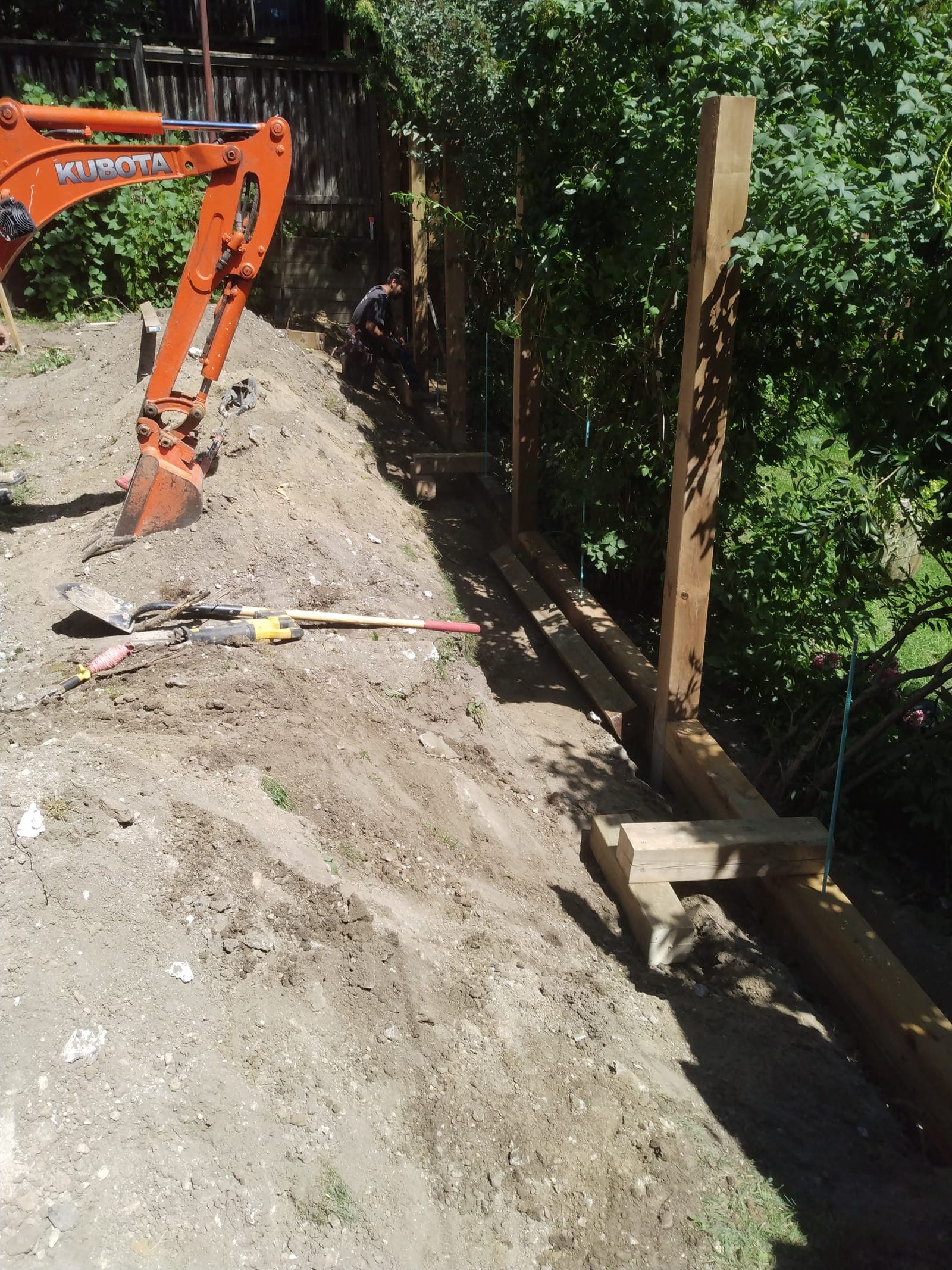 Timber retaining wall base course and support posts framed along a backyard grade change