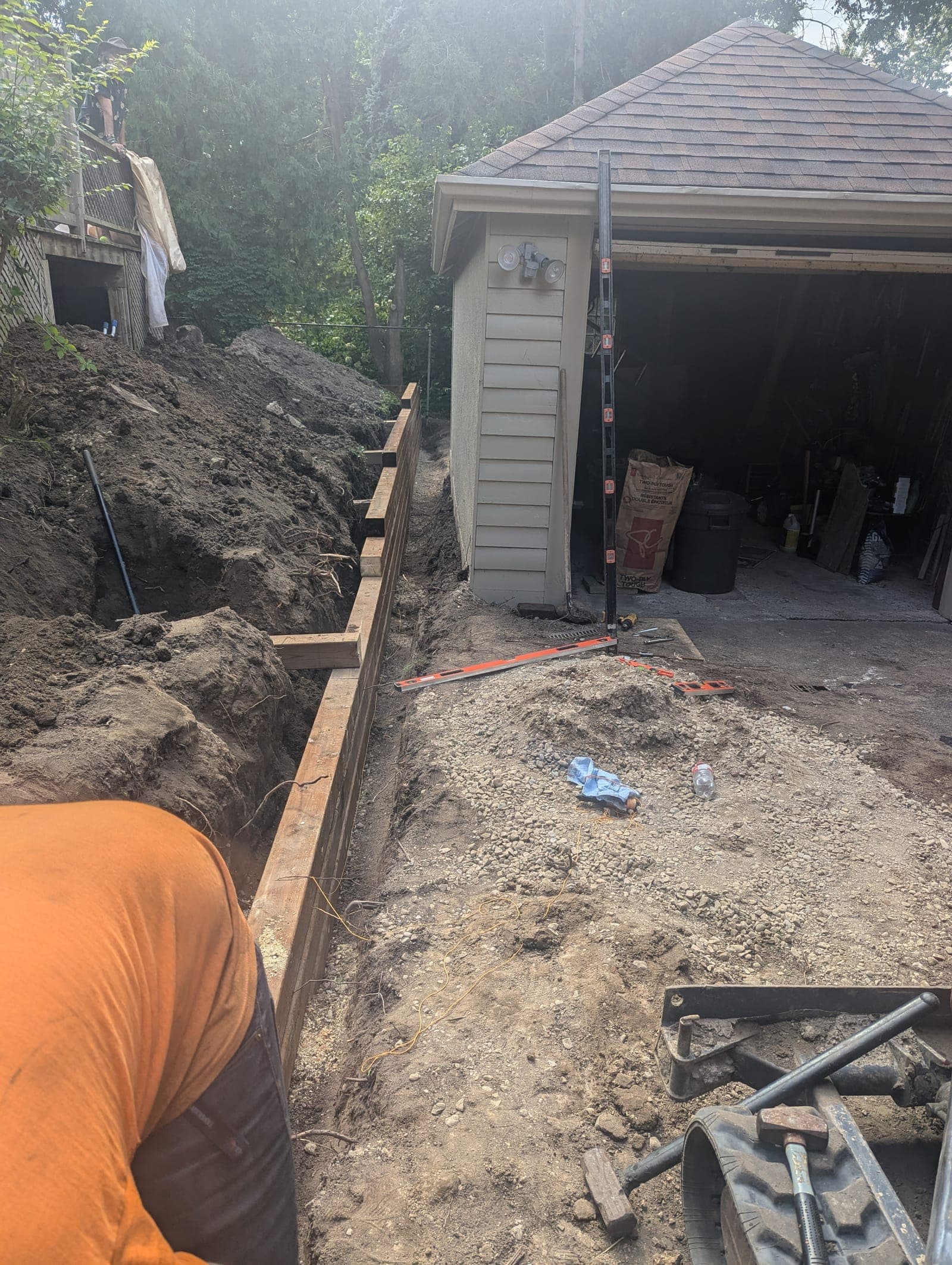 Pressure-treated timber retaining wall built beside a garage to hold back an earth bank
