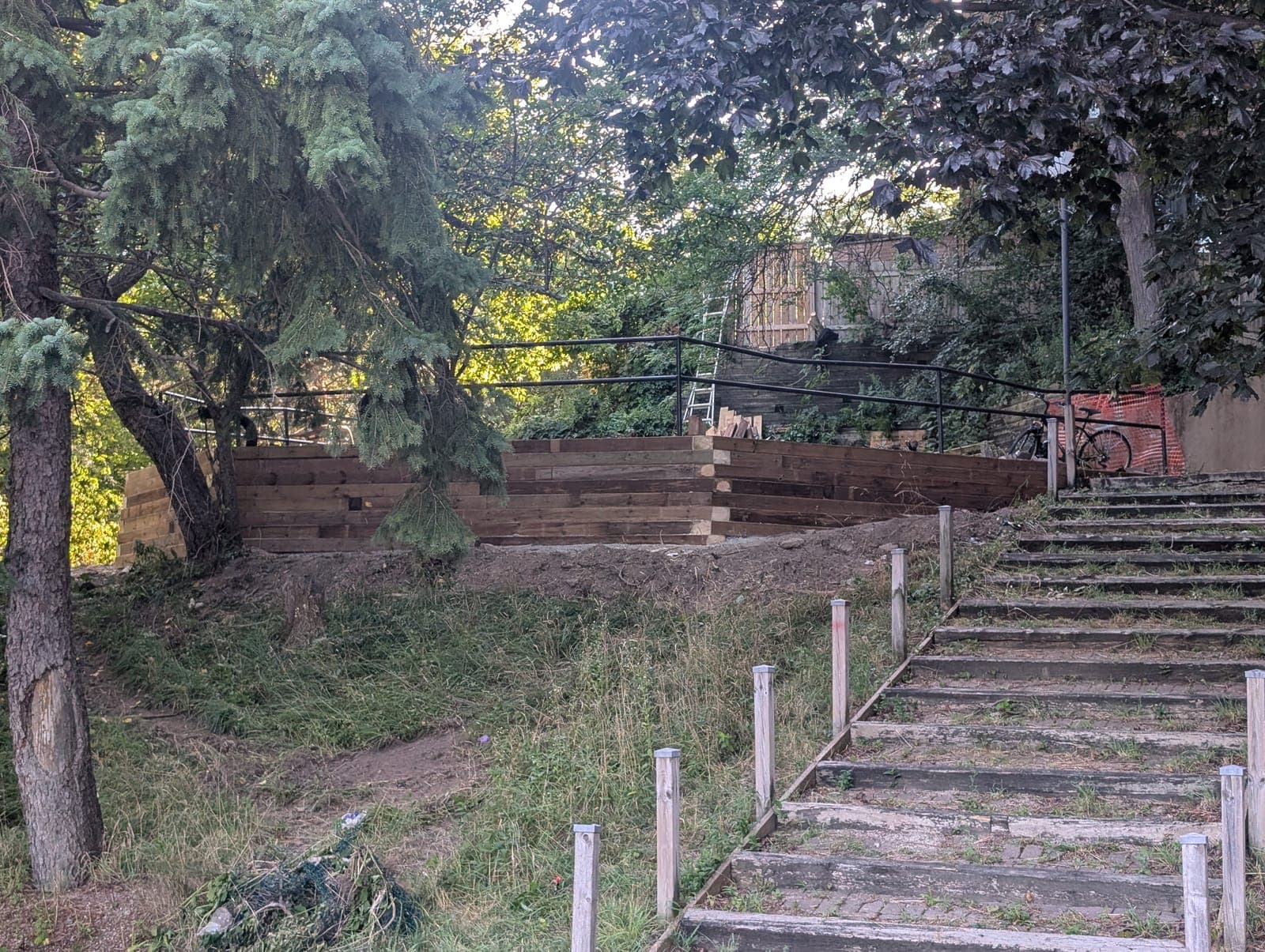 New timber retaining wall beside a set of hillside steps on a wooded embankment