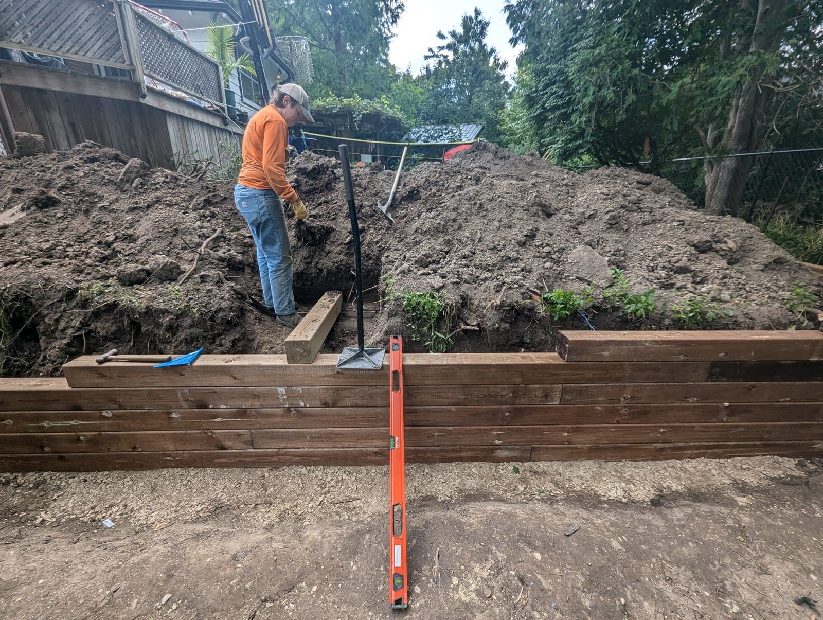 Pressure-treated timber retaining wall under construction on a backyard hillside