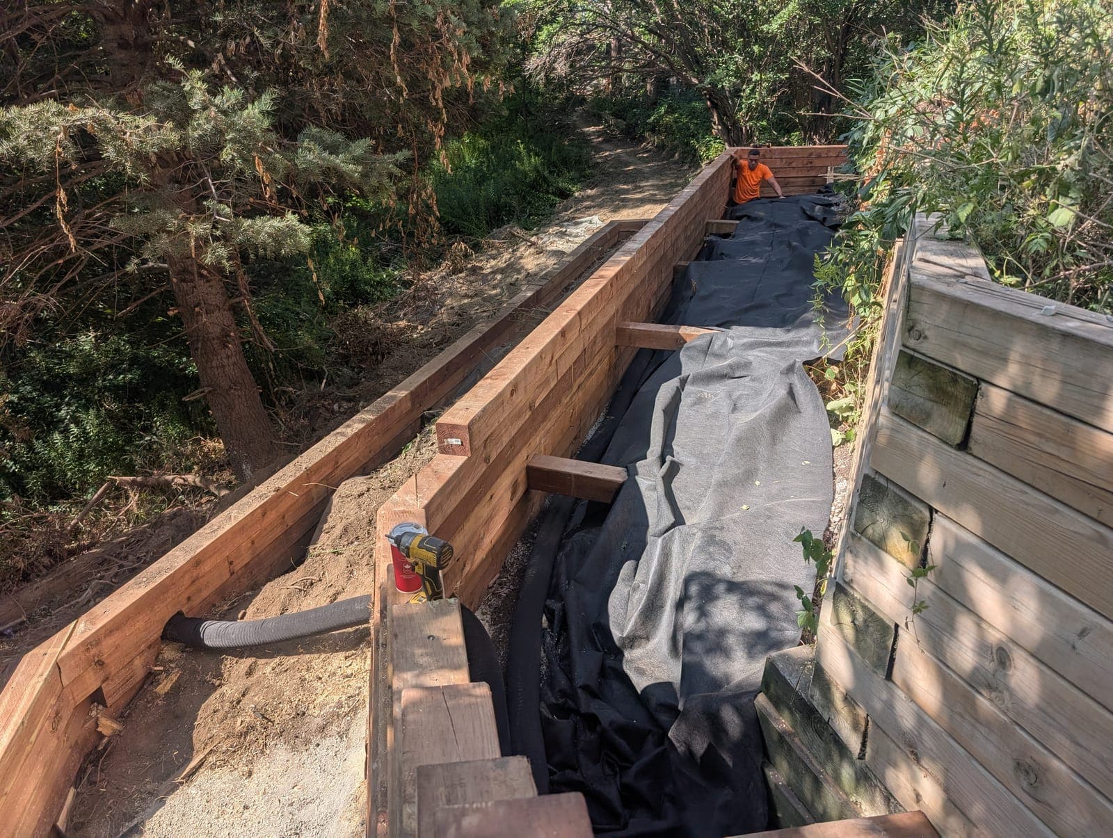 Timber retaining wall with geotextile drainage fabric being installed behind the wall