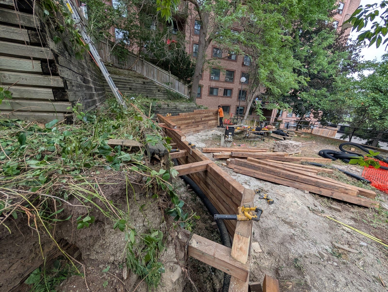 Timber retaining wall being framed with tiebacks to hold back a hillside behind an apartment building
