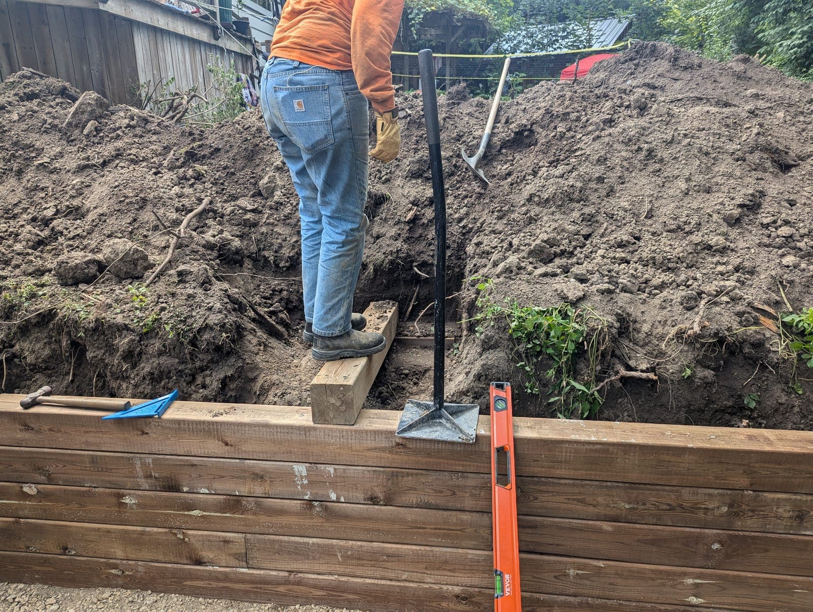 Pressure-treated timber retaining wall holding back an earth slope in a sloped backyard