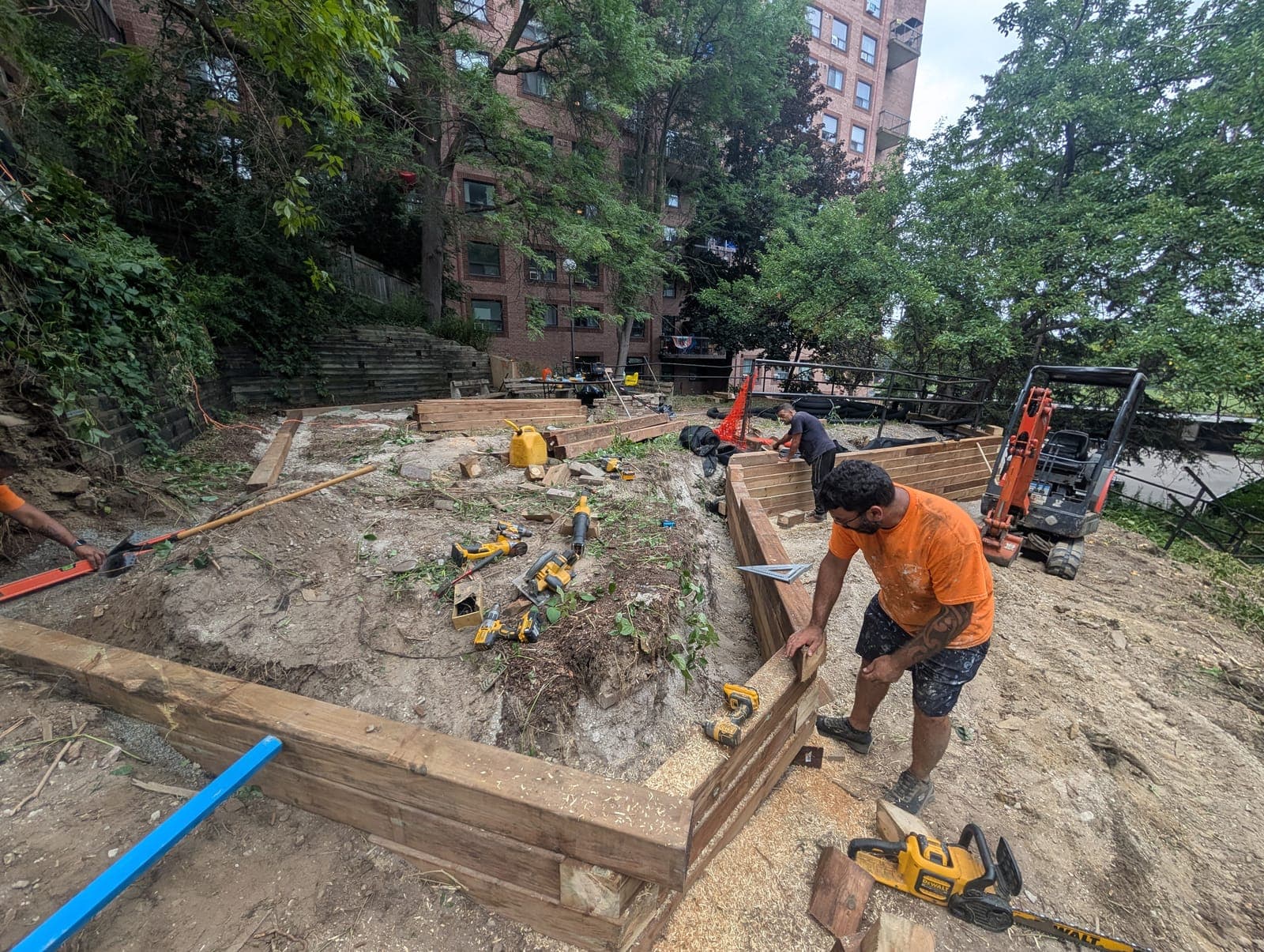 Construction crew installing a timber retaining wall on a landscaped slope