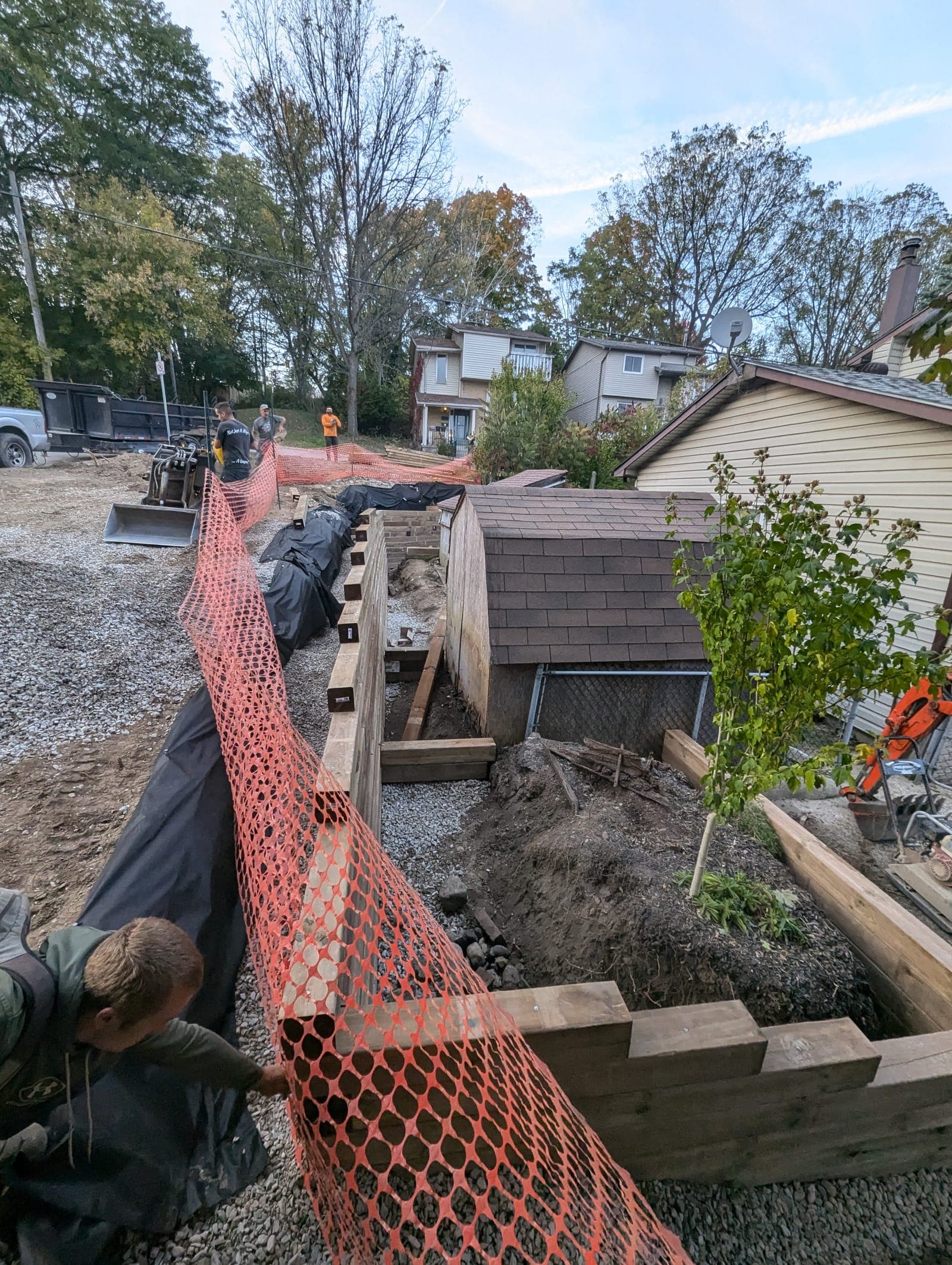 Timber retaining wall under construction along a residential property line