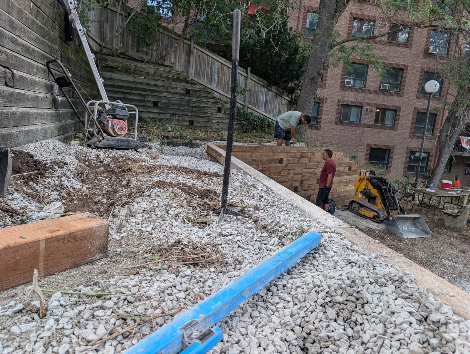 Timber retaining wall construction jobsite terracing a hillside behind an apartment building