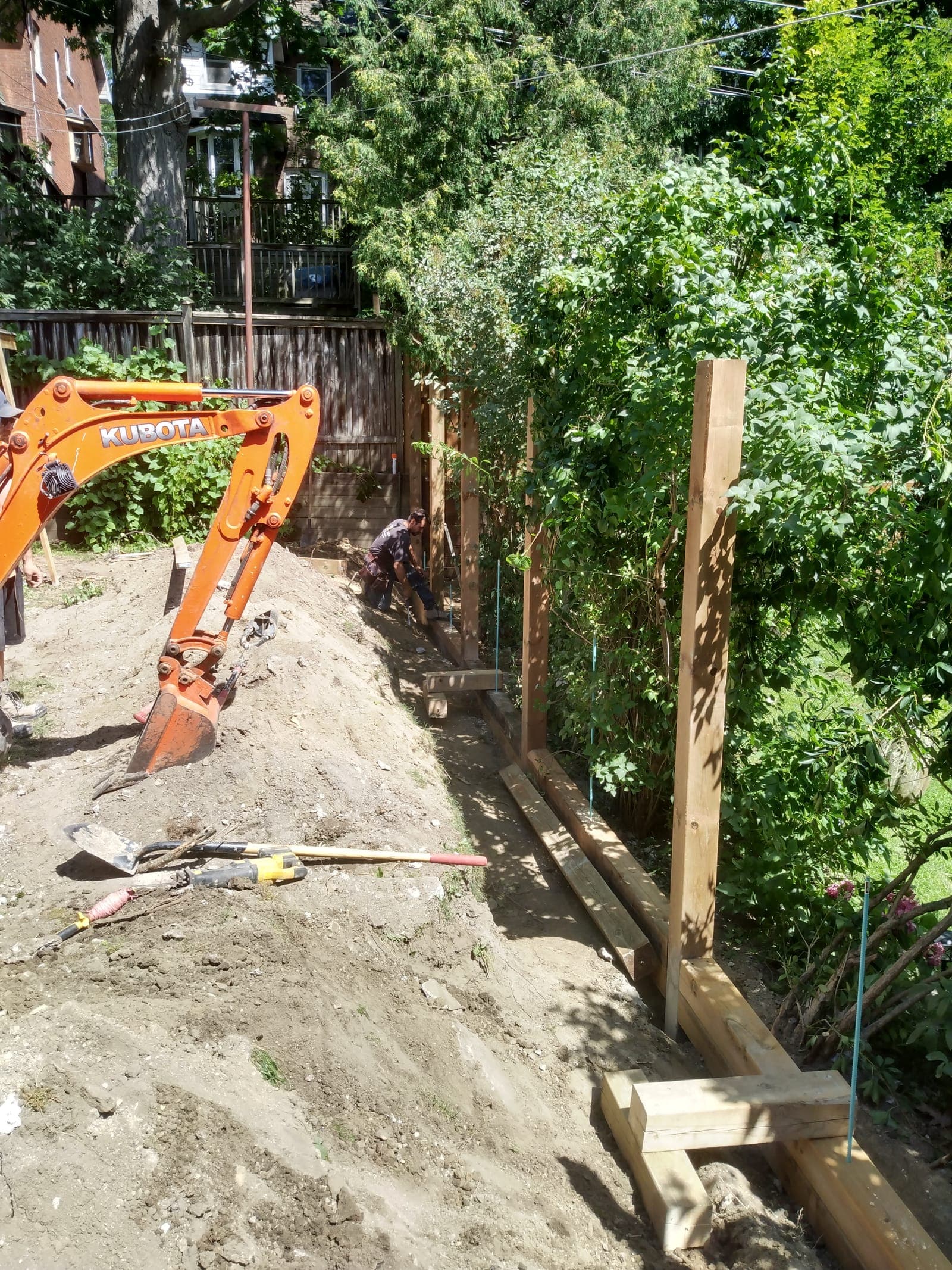 Wooden timber retaining wall framing with posts and horizontal rails along a garden slope
