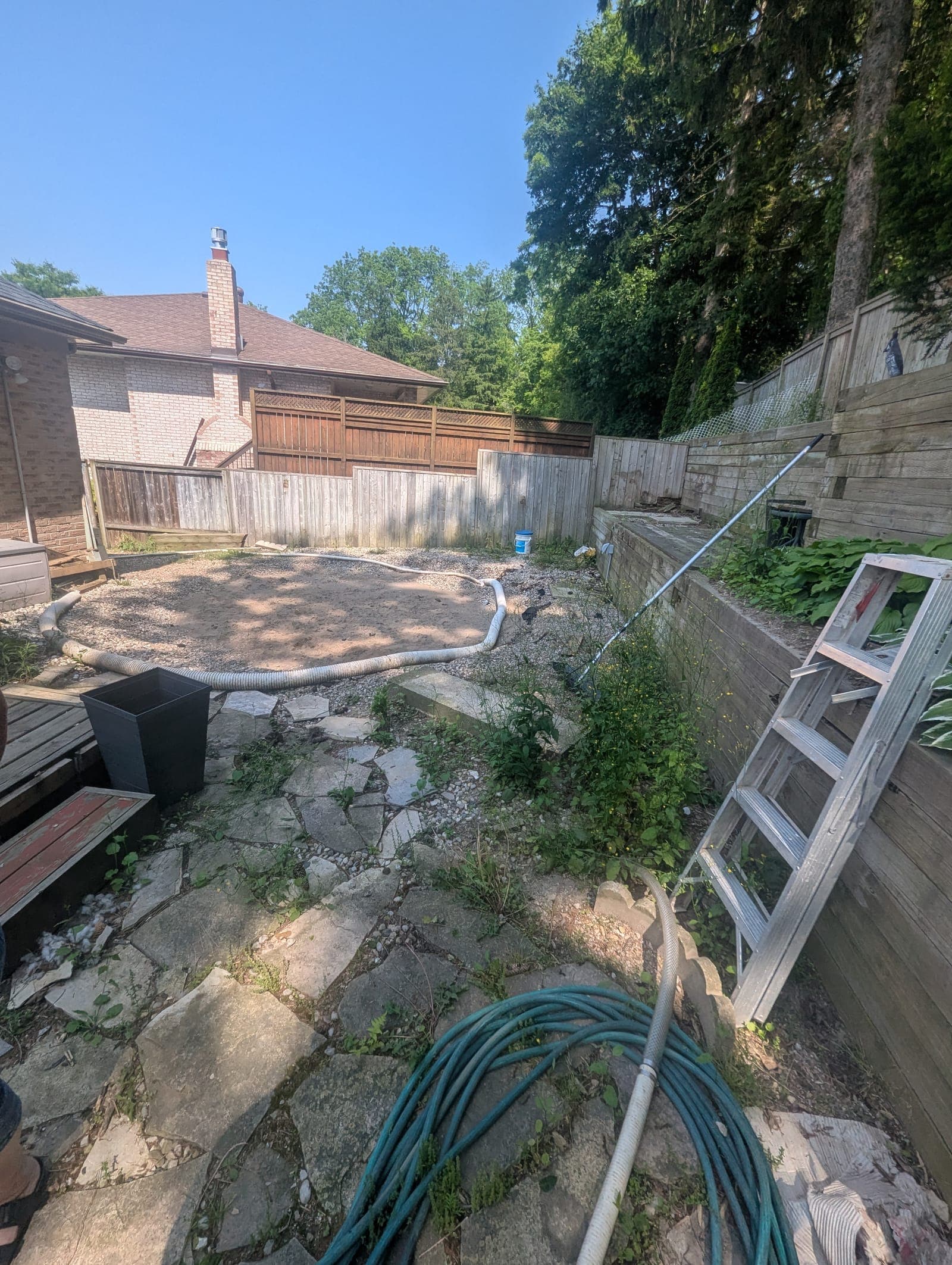 Two-tier timber retaining wall supporting a raised hosta garden bed along a backyard fence