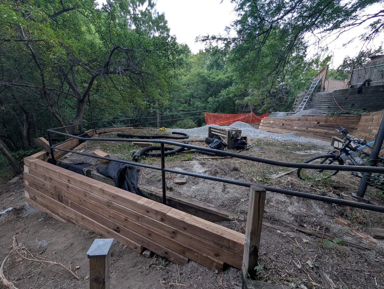 Raised timber retaining wall terrace with a metal railing overlooking a landscaped yard
