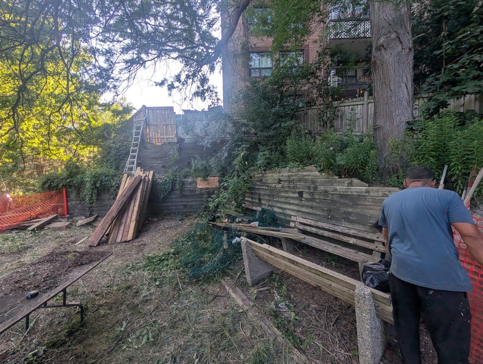 Timber retaining wall rebuild in progress on a shaded residential slope
