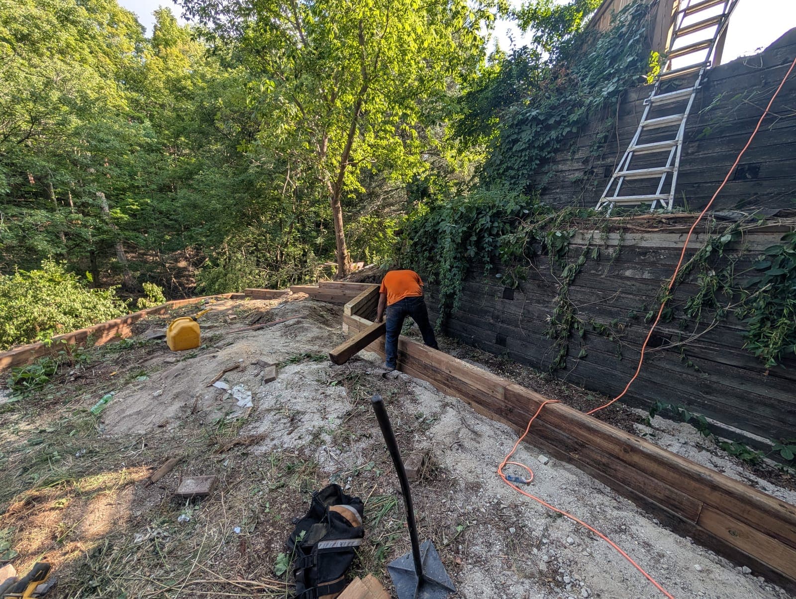 Timber retaining wall being rebuilt on a terraced wooded hillside in a Southwestern Ontario backyard