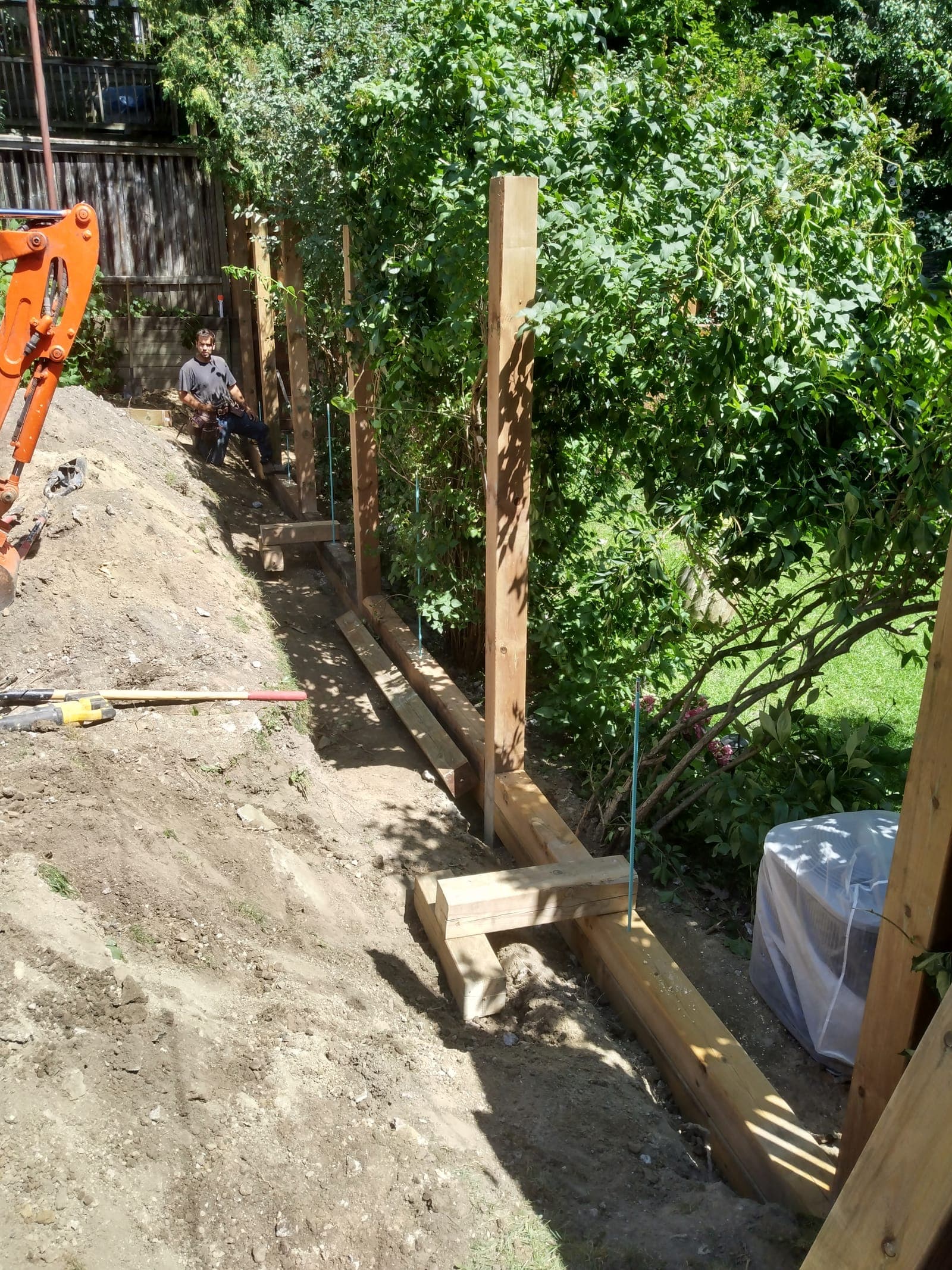 Timber retaining wall construction with vertical posts and tie-back deadman supports