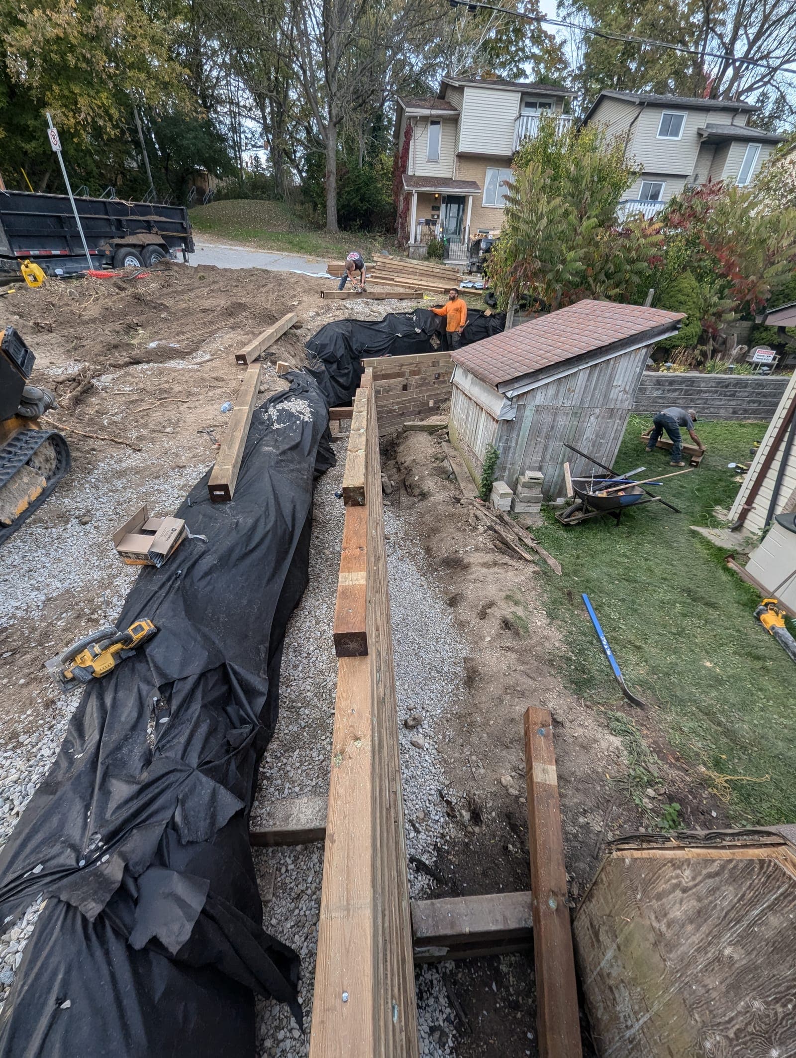 Timber retaining wall installation with waterproofing membrane and gravel drainage