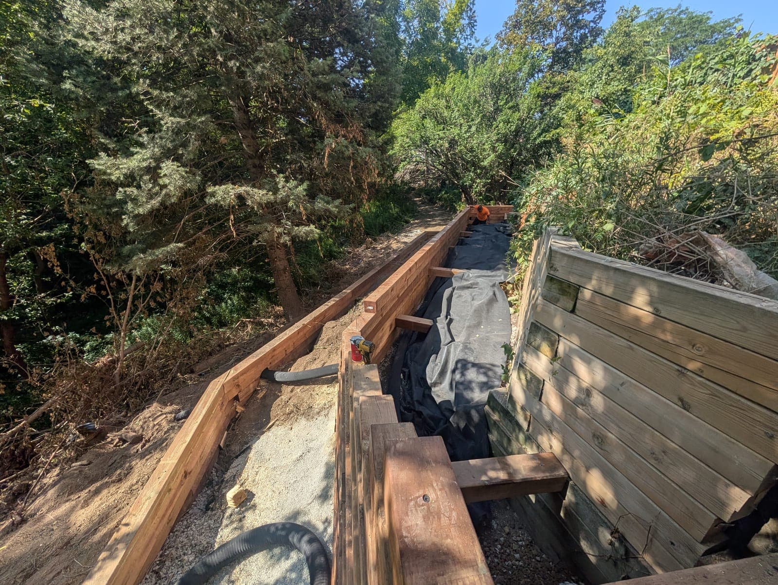 Timber retaining wall with a gravel and drainage system built behind the wall on a slope