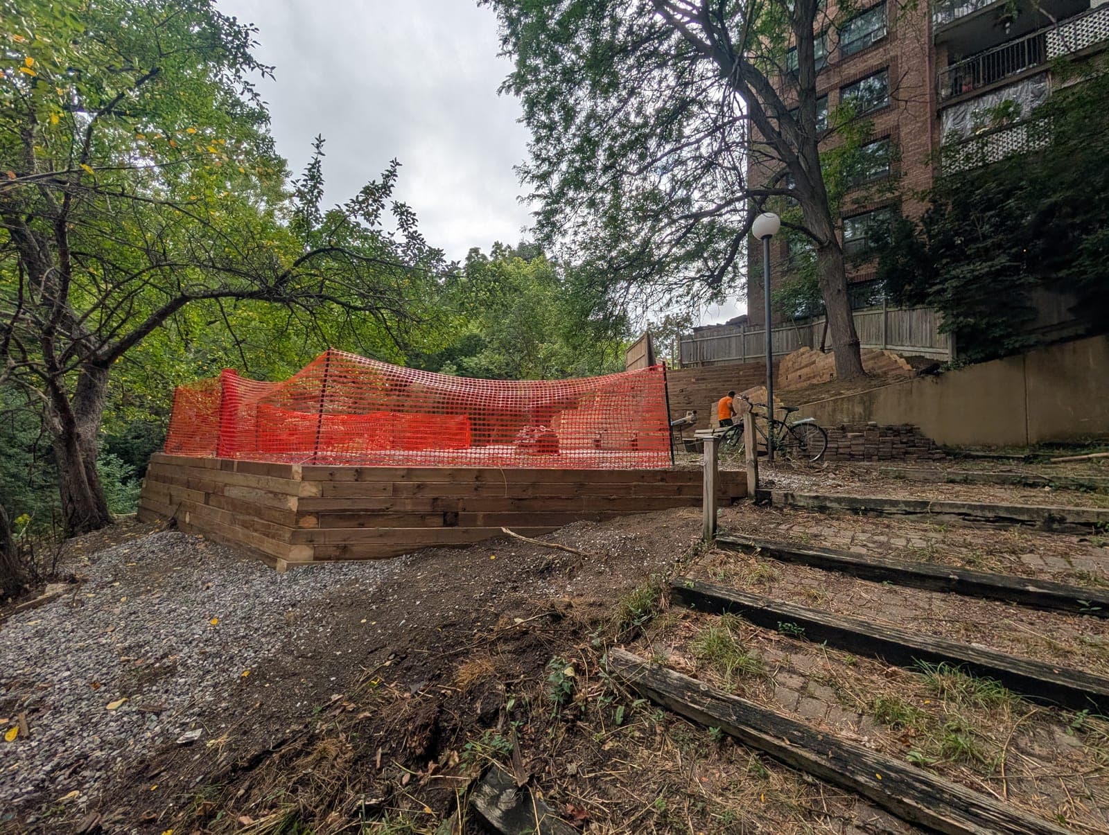Curved timber retaining wall with adjacent garden steps on a wooded urban slope